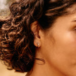 Close-up of a woman with curly hair and a red top, outdoors.