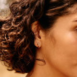 Close-up of a woman with curly hair and a red top, outdoors.