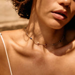 Close-up of a person wearing a delicate necklace with a neutral background