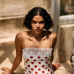 Woman wearing a polka dot dress sitting on a stone surface.