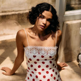 Woman wearing a polka dot dress sitting on a stone surface.
