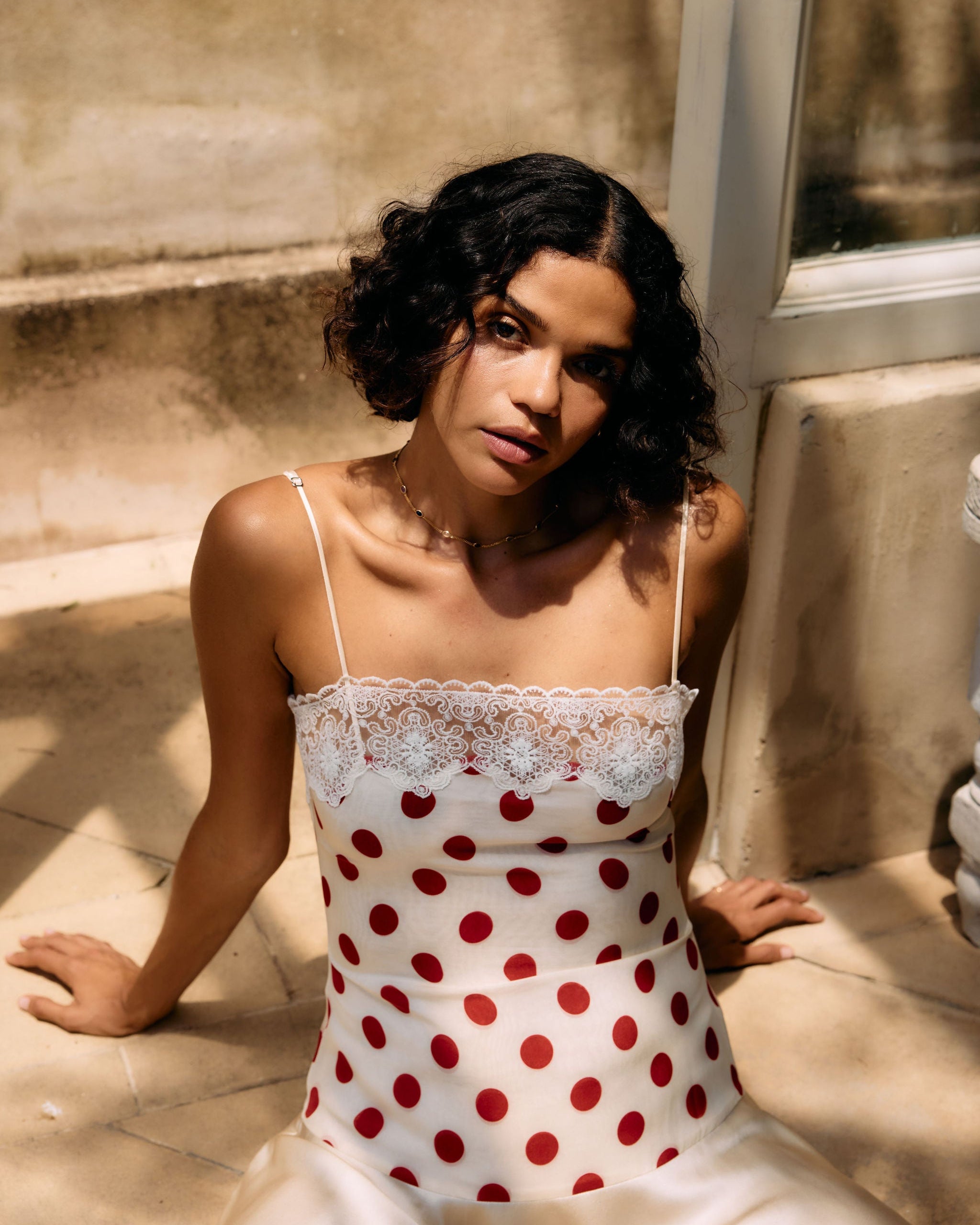 Woman wearing a polka dot dress sitting on a stone surface.
