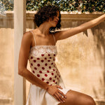 Woman in a polka dot dress standing outdoors with greenery in the background