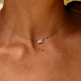 Close-up of a necklace with a small pendant on a person's neck.