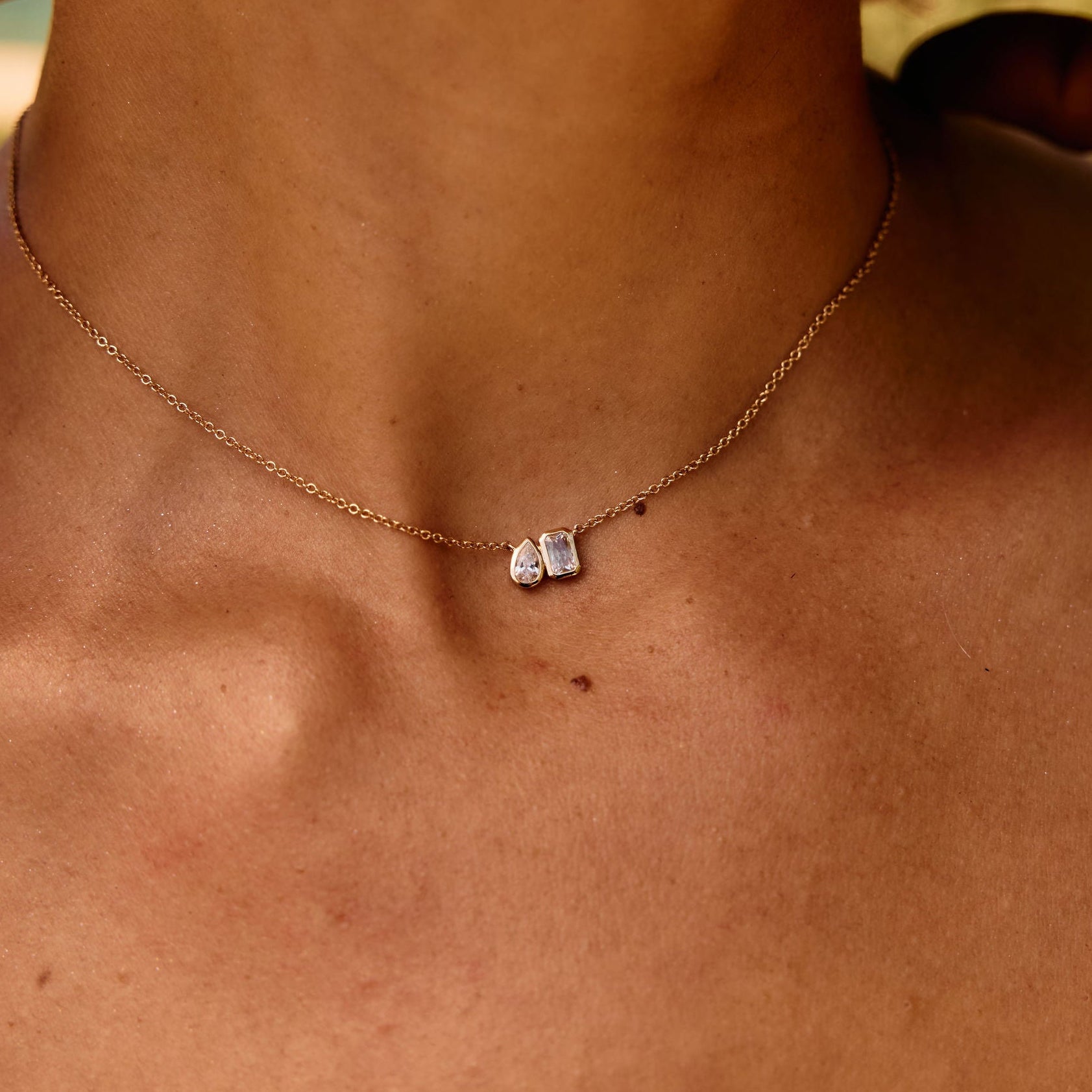 Close-up of a necklace with a small pendant on a person's neck.
