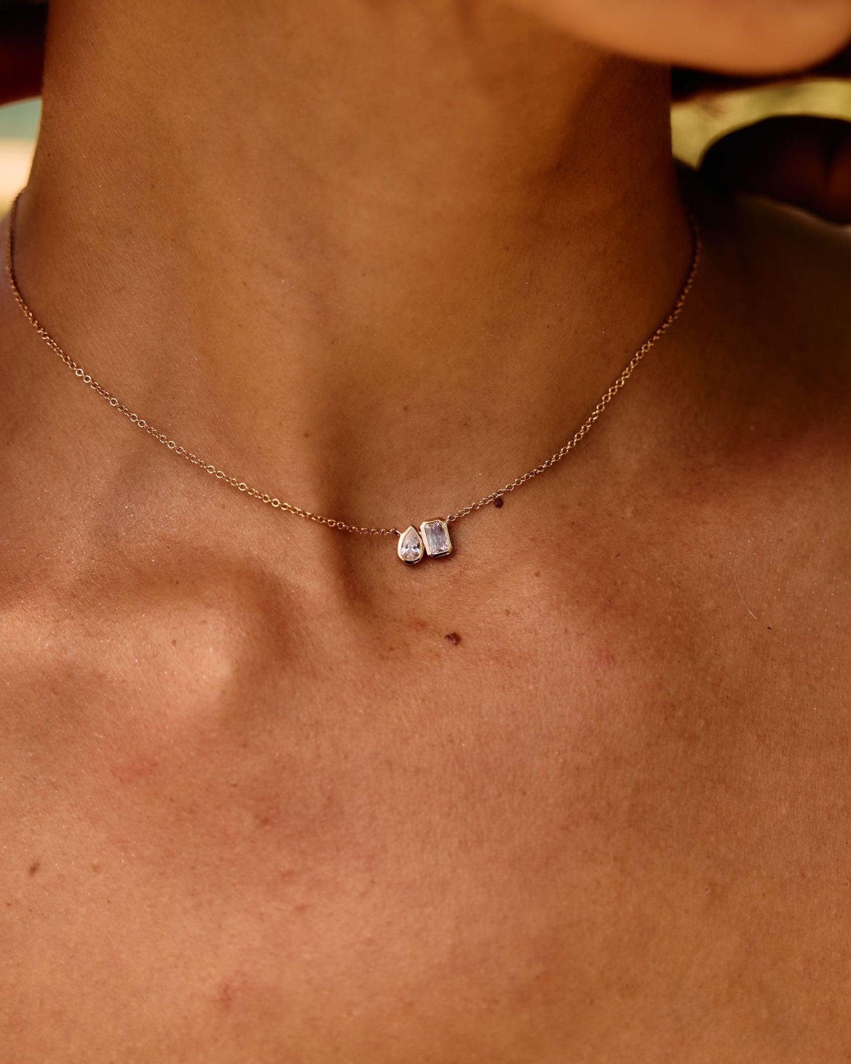 Close-up of a necklace with a small pendant on a person's neck.