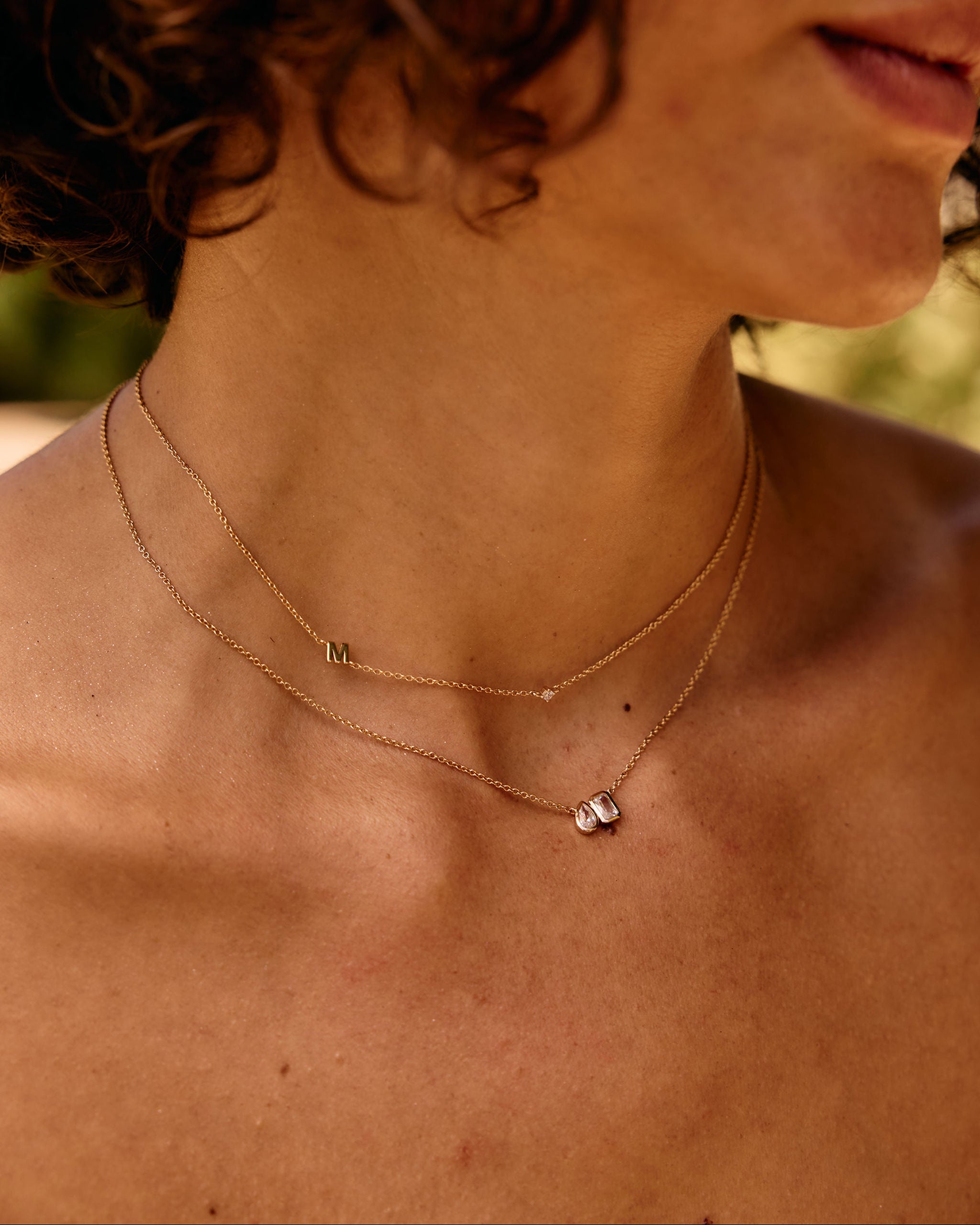 Close-up of a person wearing a delicate necklace with small pendants.