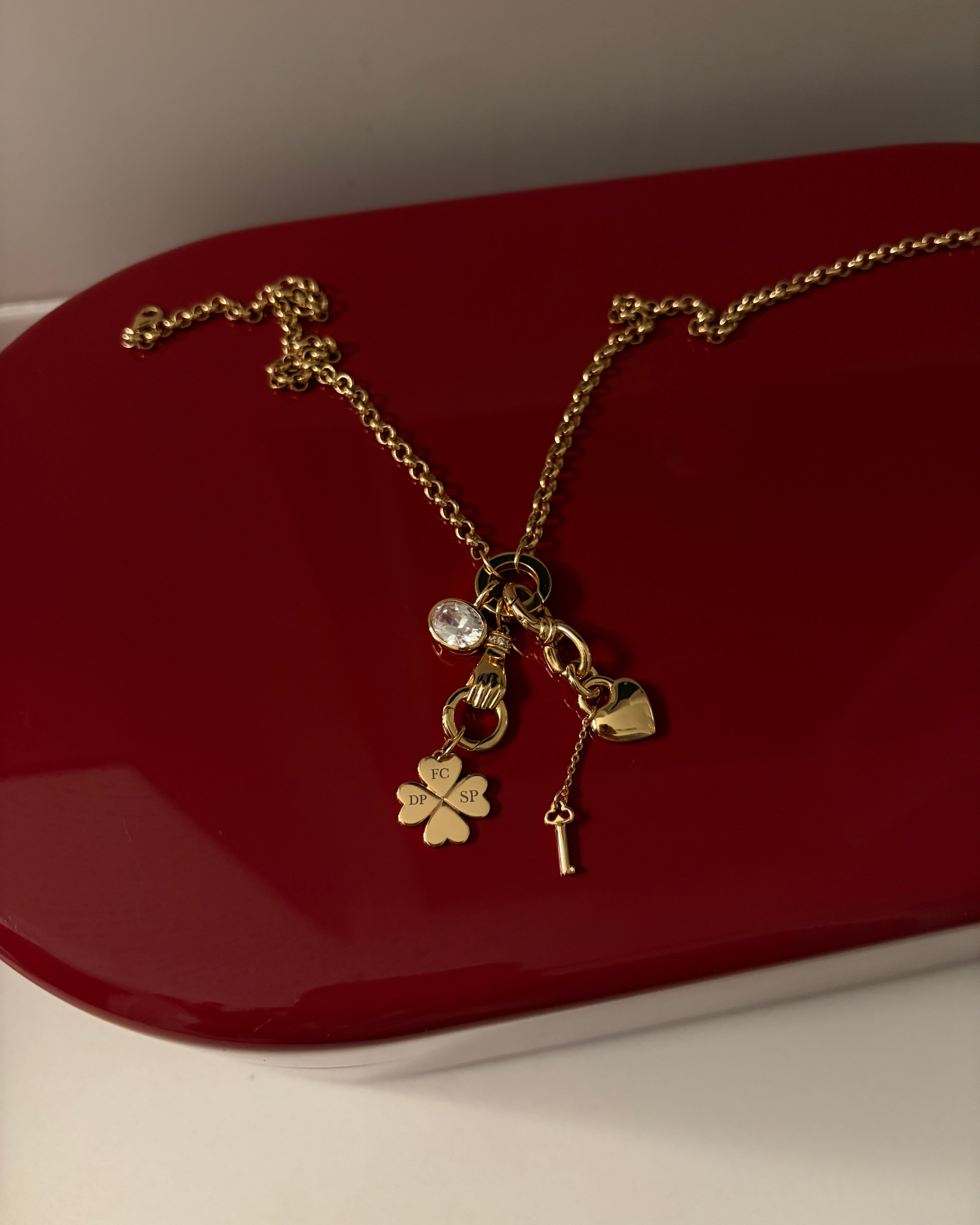 Gold necklace with charms on a red surface