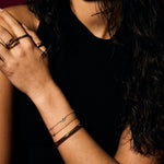 Close-up of a person's arm with multiple evil eye bracelets and rings