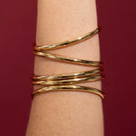 Gold bracelet on a wrist against a red background