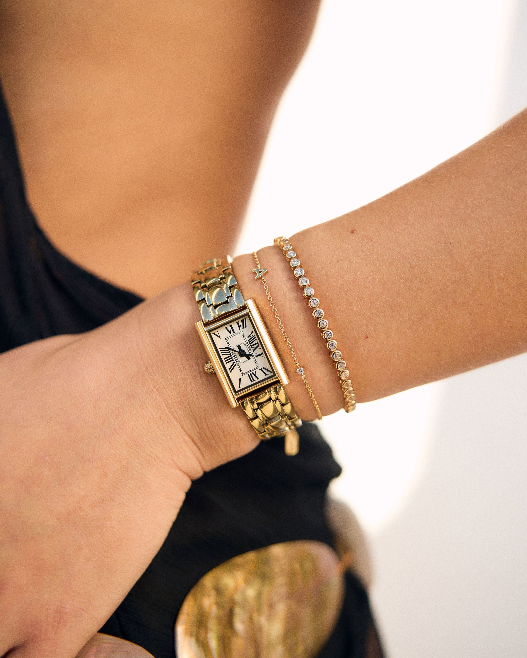 Gold watch and bracelet on a wrist with a blurred background