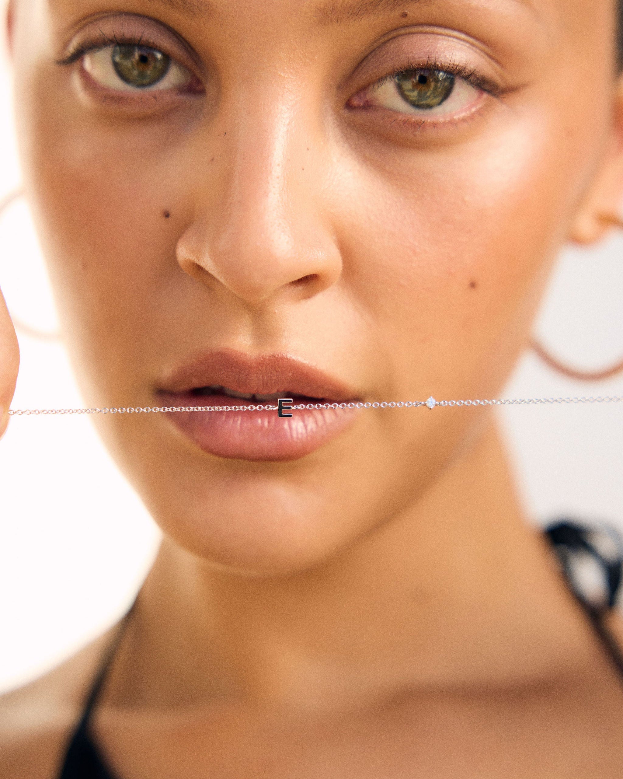 Close-up of a woman's face with a Sterling silver letter bracelet