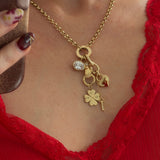 Gold necklace with charms worn by a person in a red lace garment.