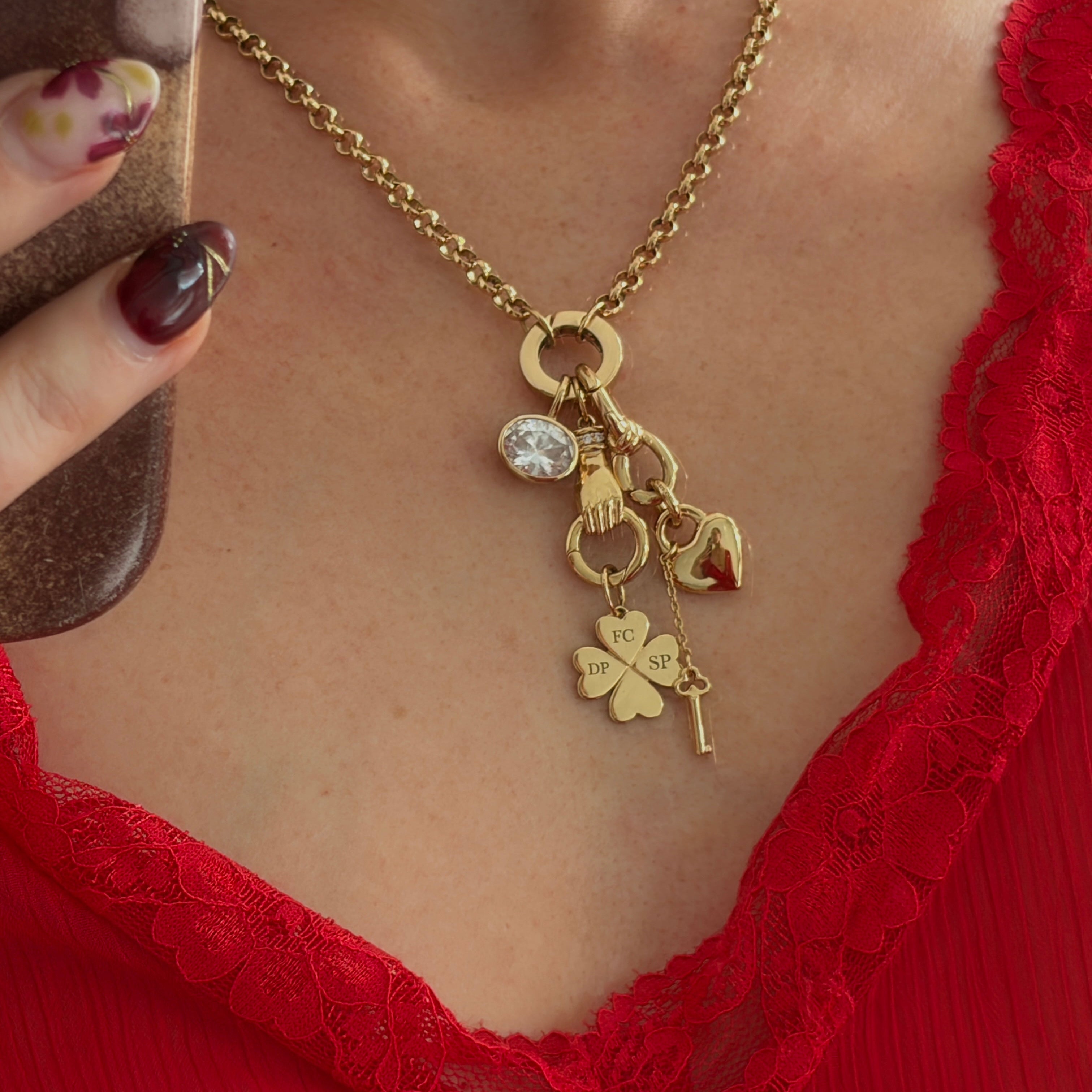 Gold necklace with charms worn by a person in a red lace garment.