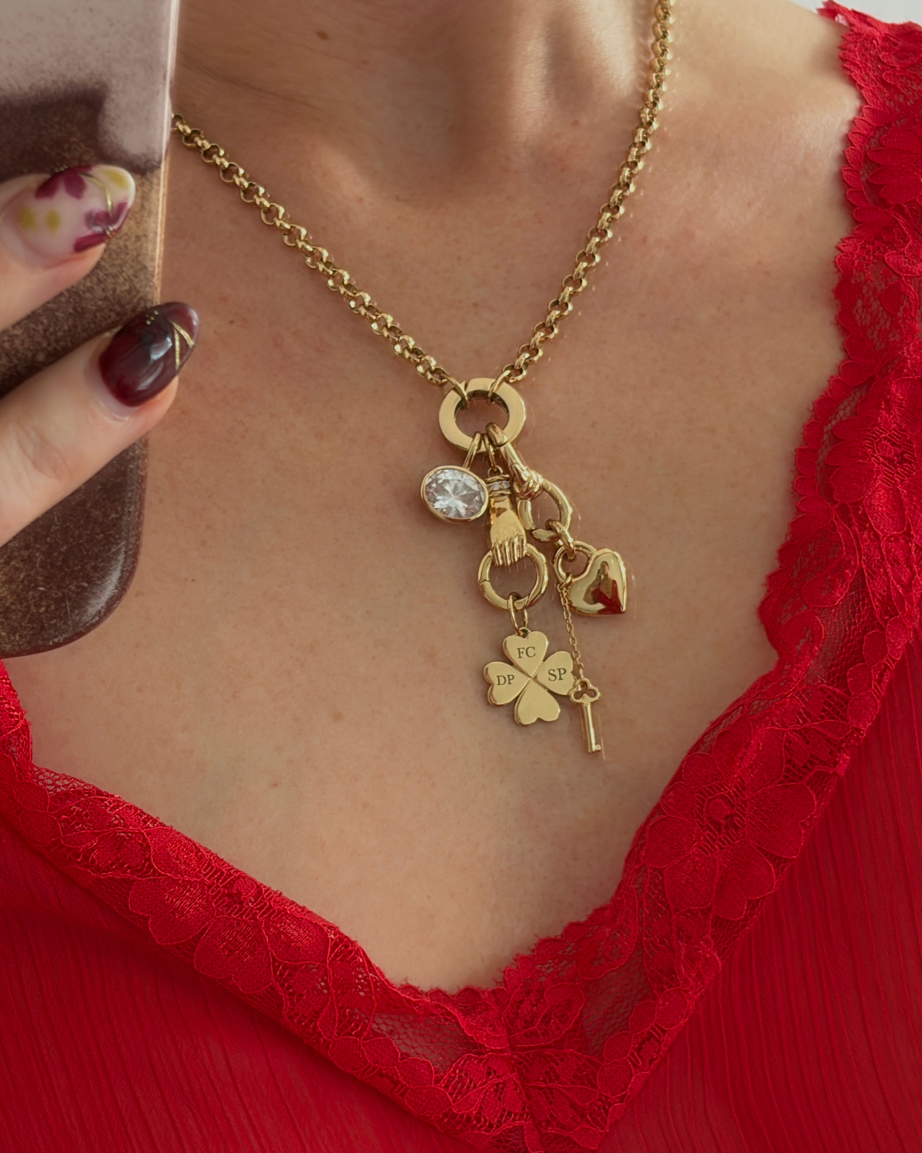 Gold necklace with charms worn by a person in a red lace garment.