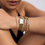 Close-up of a person's arm wearing a gold watch and bangles 