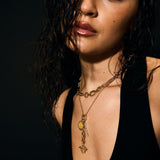 Woman wearing a black top and gold necklace against a dark background