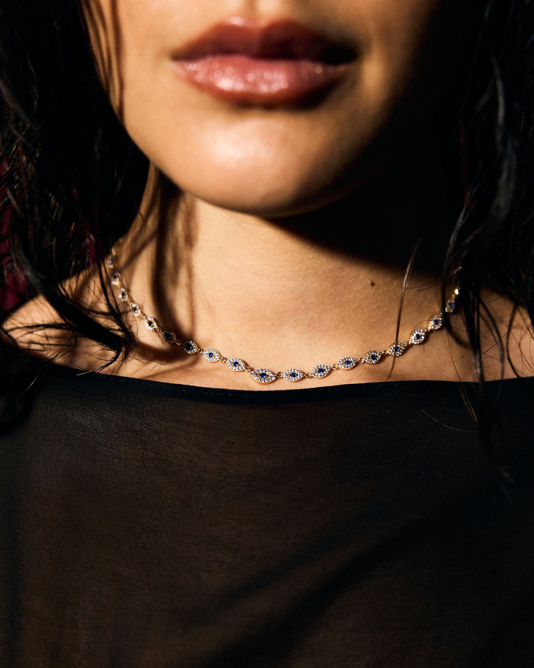 Close-up of a person wearing a delicate necklace with a dark background