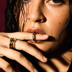 Close-up of a person with multiple rings on their fingers against a dark background