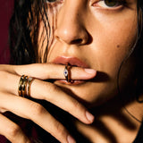 Close-up of a person with multiple rings on their fingers against a dark background