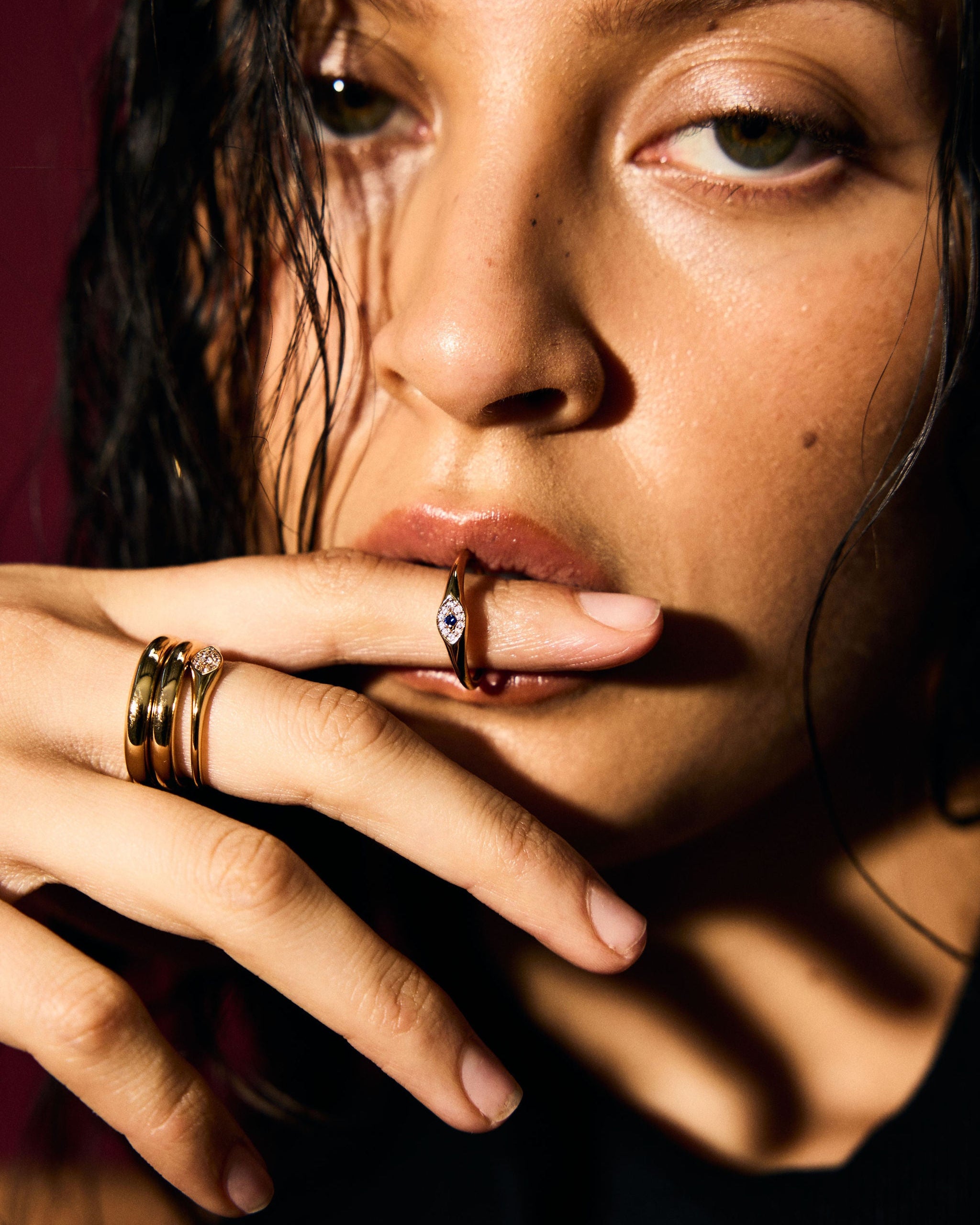 Close-up of a person with multiple rings on their fingers against a dark background