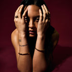 Person with hands on face against a dark red background