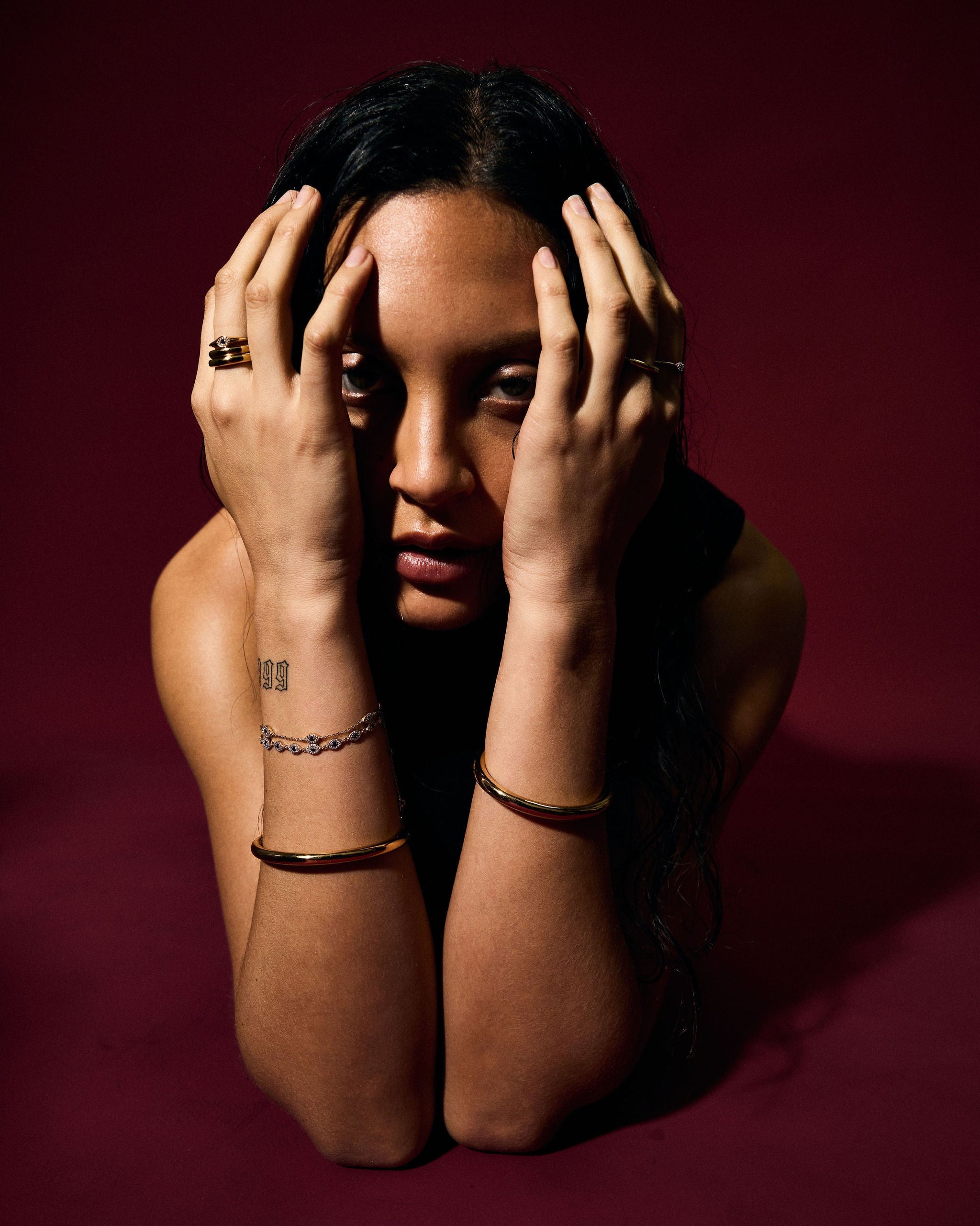 Person with hands on face against a dark red background