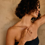 Woman with curly hair wearing a black dress against a beige wall