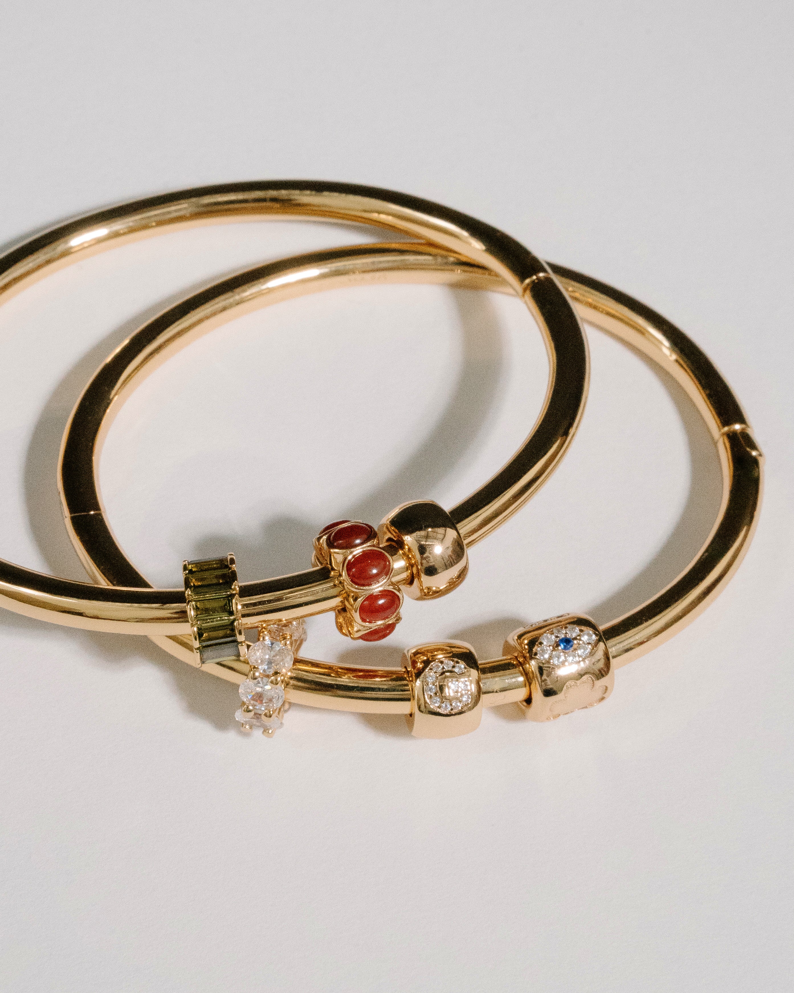 Gold bangles with gemstone accents on a light gray background