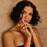 Woman with curly hair against a beige wall