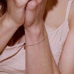 A delicate rose gold chain bracelet worn on a woman's wrist, shown in a close-up lifestyle shot with her hands clasped in front of her face.