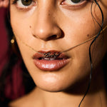 Close-up of a woman's face with a gold chain around her neck.
