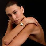 Woman wearing a gold watch on a black background