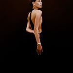 Woman wearing a black dress with a deep neckline against a dark background