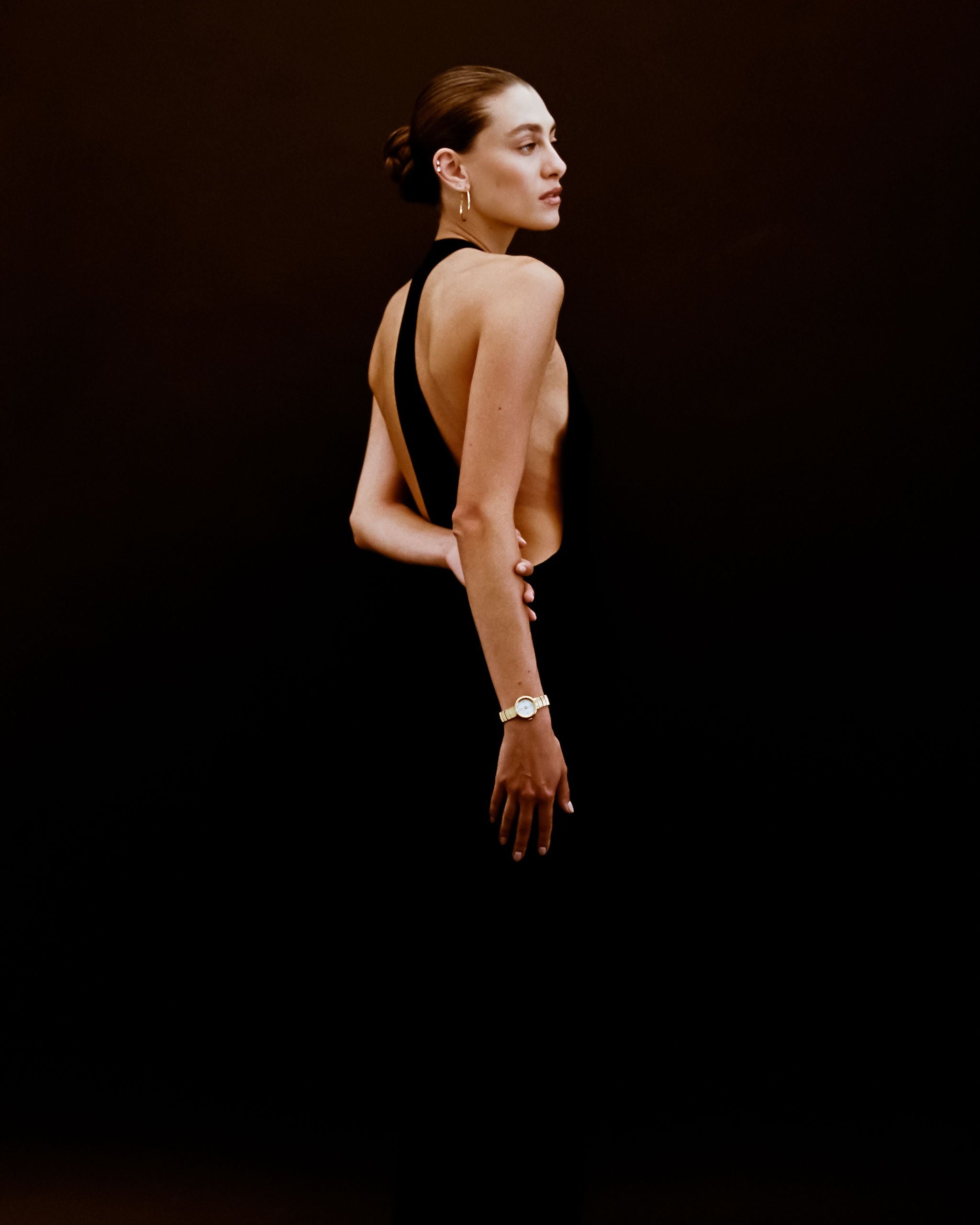 Woman wearing a black dress with a deep neckline against a dark background