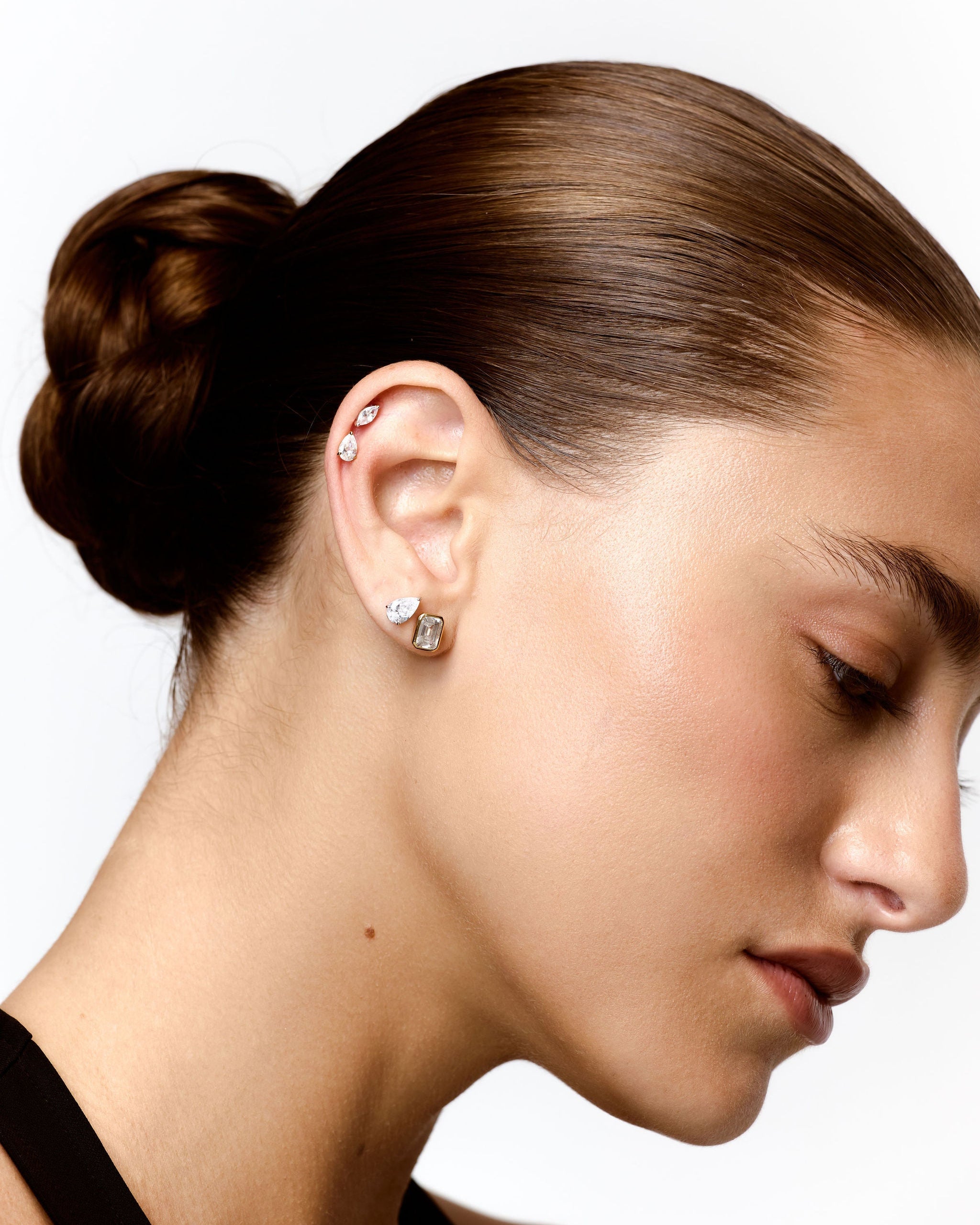 Close-up of a woman's ear with earrings against a white background