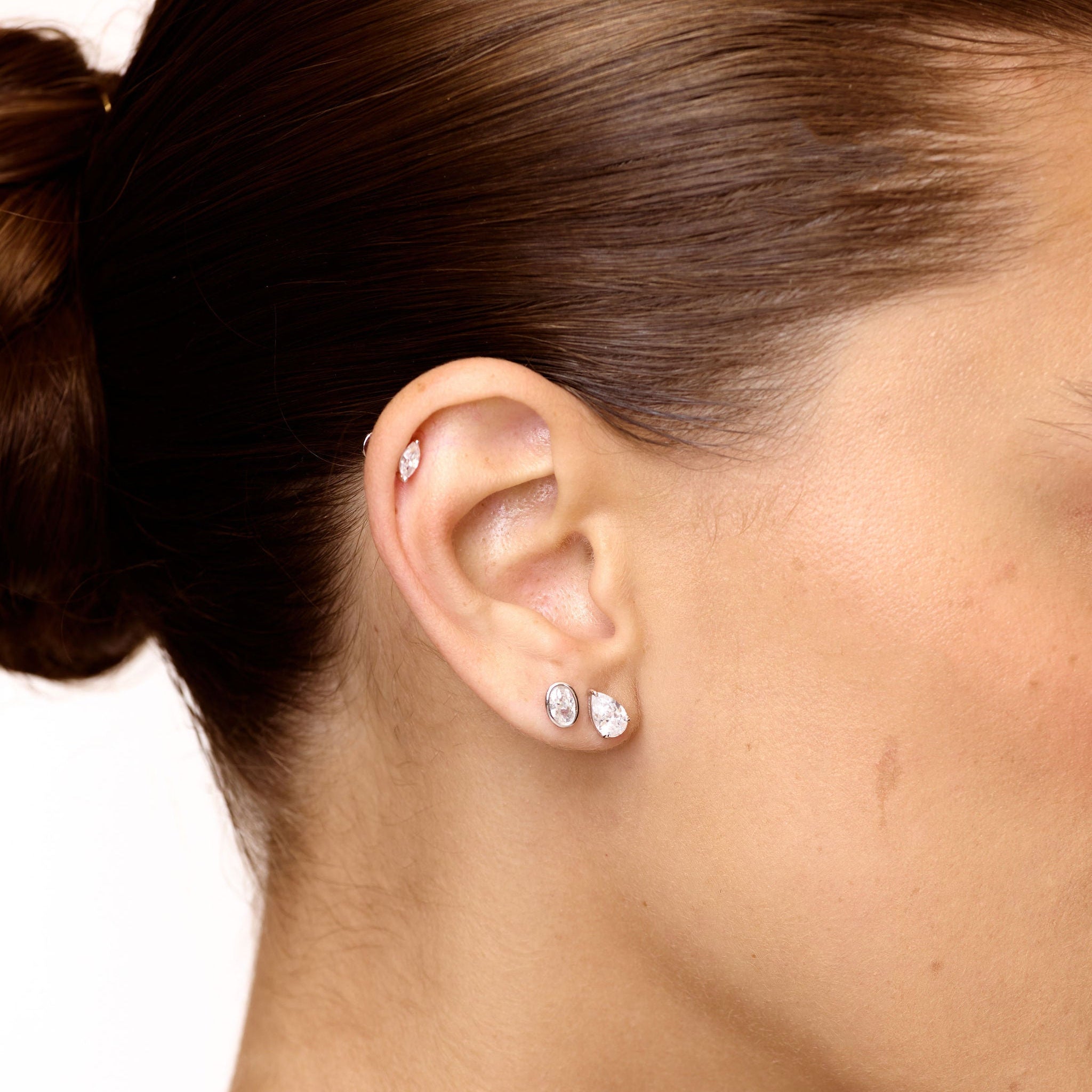 Close-up of an ear wearing a small earring with a plain background