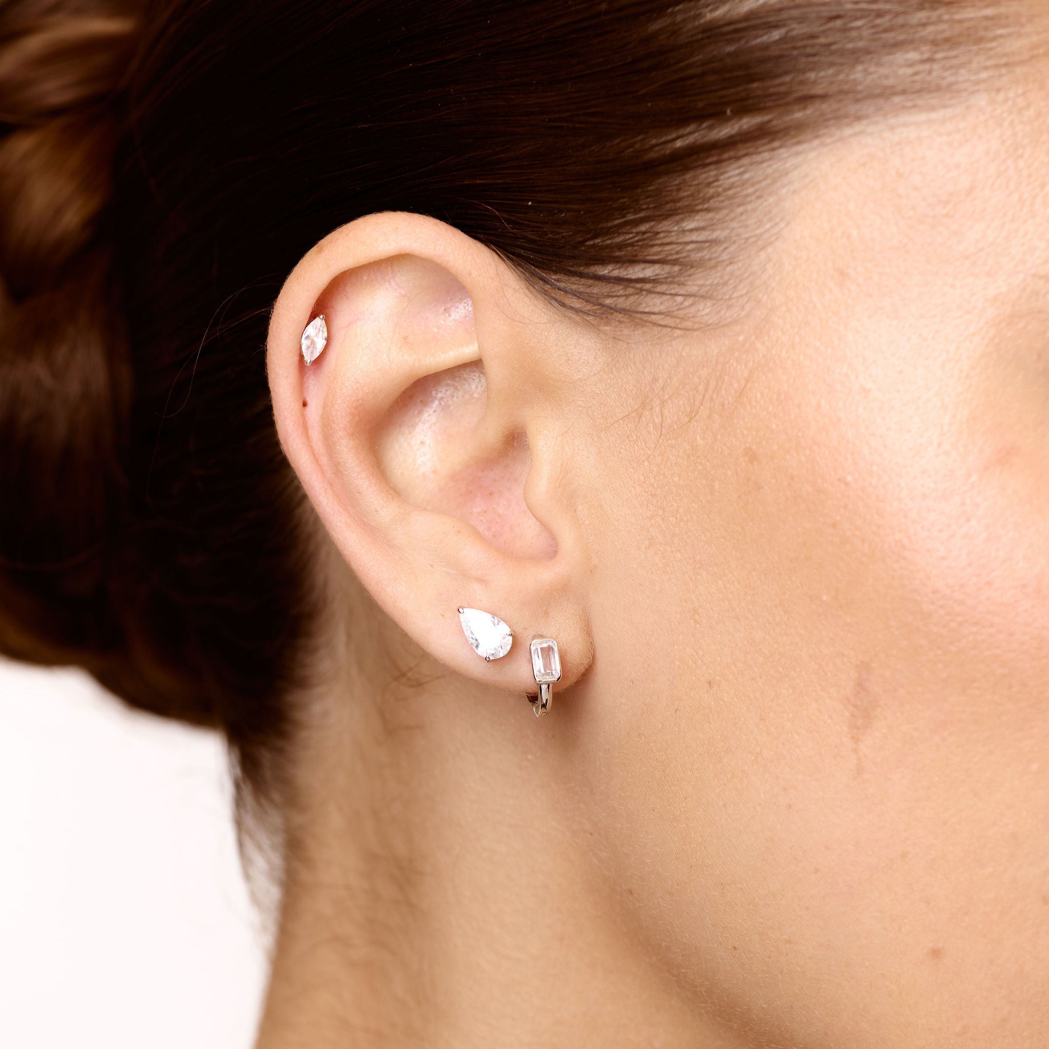 Close-up of a person wearing small earrings with a plain background