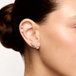 Close-up of a person wearing earrings with a neutral background