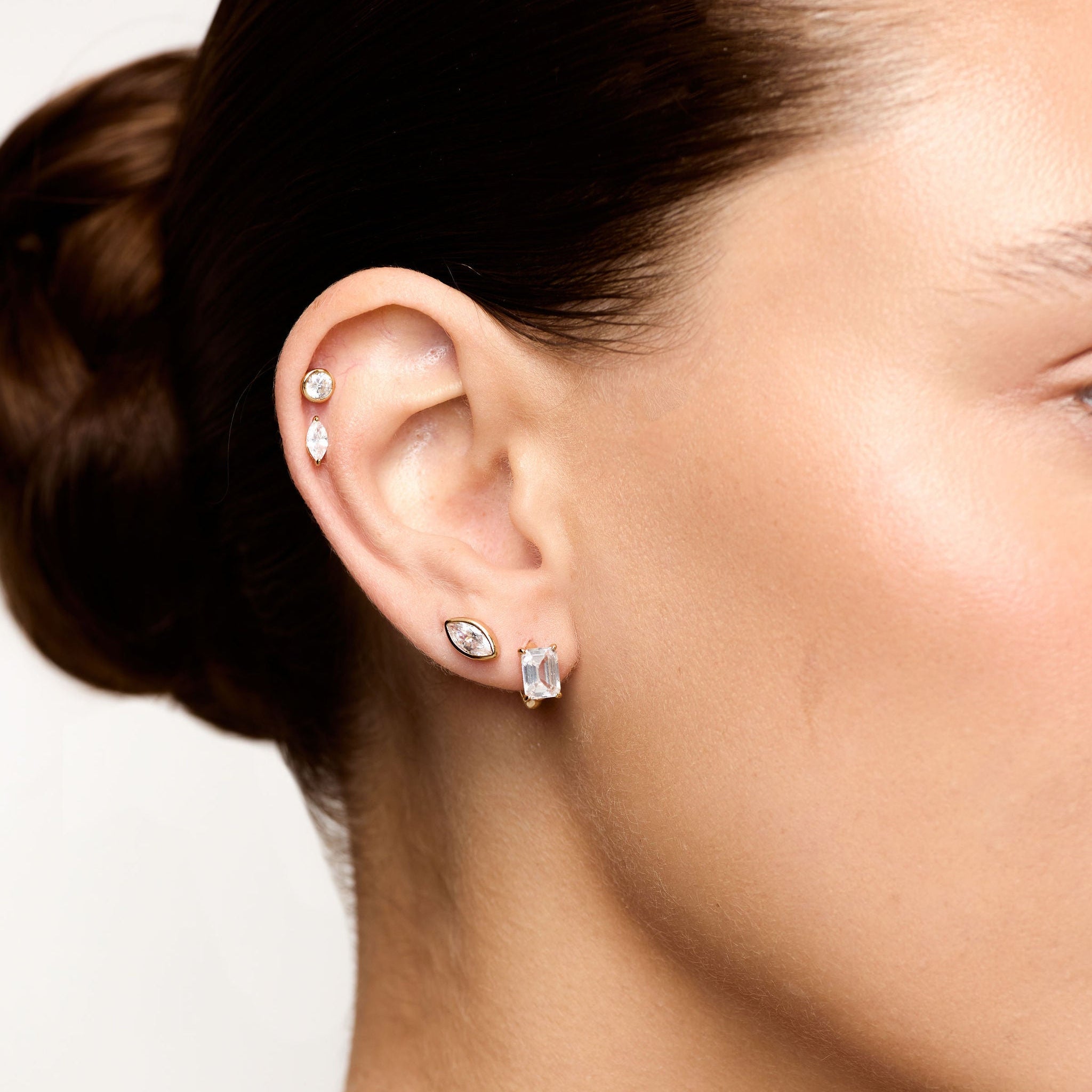 Close-up of a person wearing earrings with a neutral background