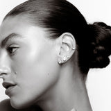 Black and white close-up of a woman's ear with earrings and hair styled in an updo.