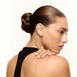 Woman with a stylish hair bun wearing earrings on a white background
