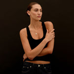 Person wearing a black tank top and jeans against a dark background