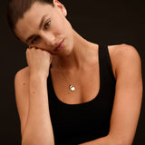 Woman wearing a black tank top against a dark background
