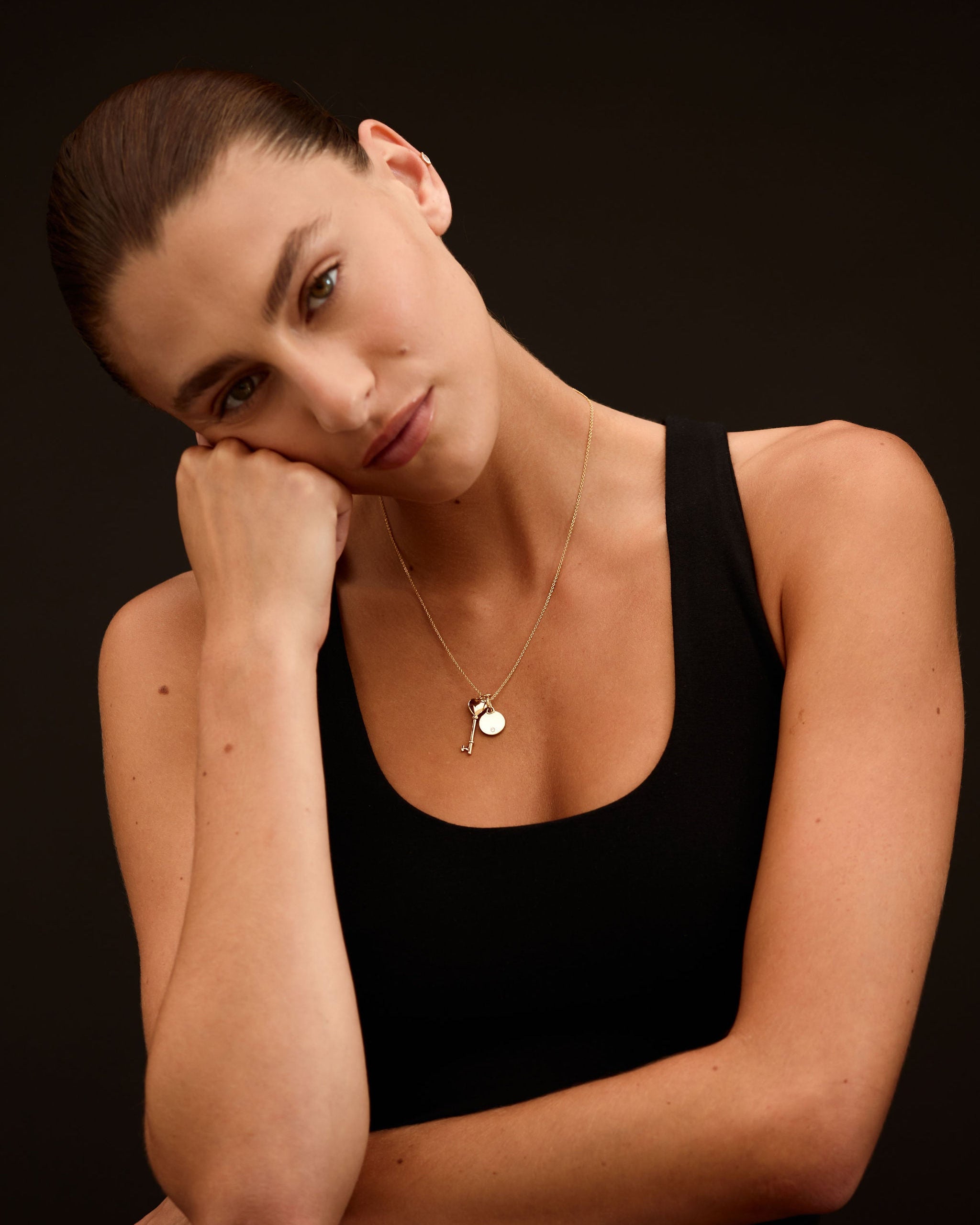 Woman wearing a black tank top against a dark background