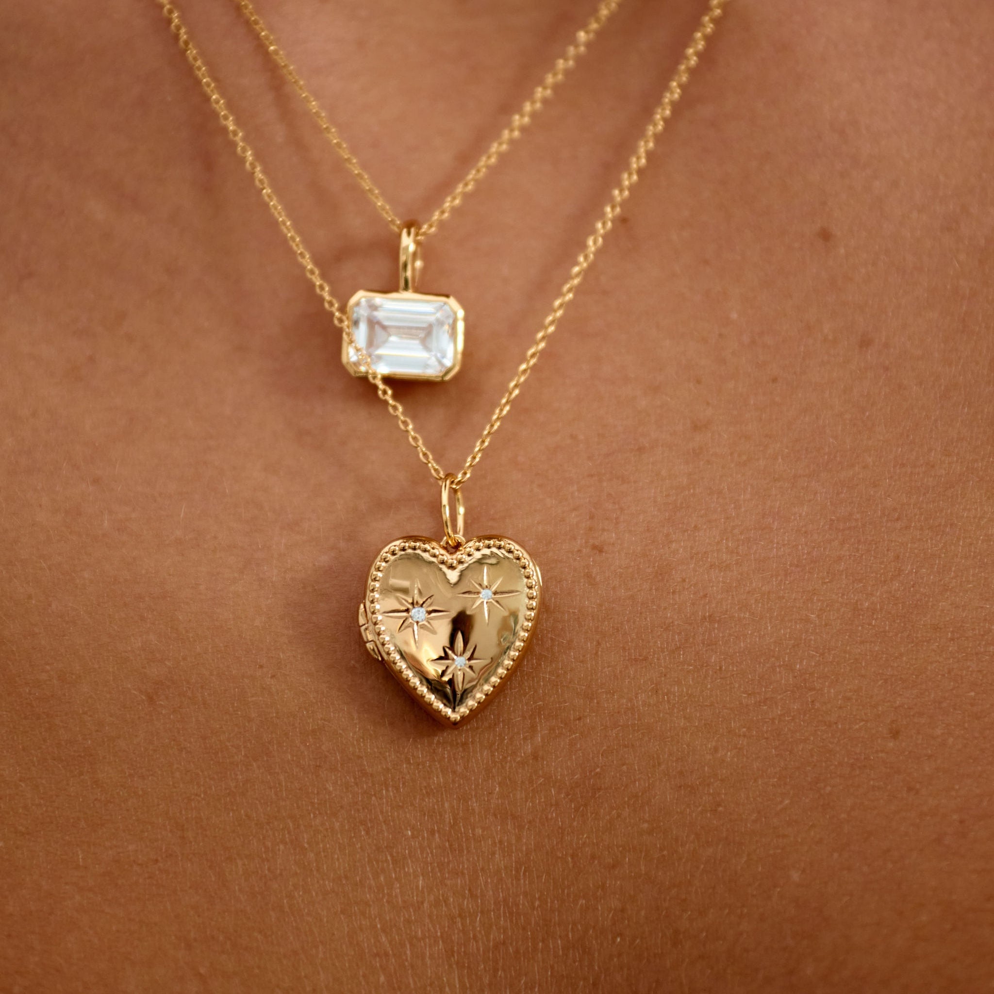 Gold necklaces with heart-shaped and star pendants on a skin background