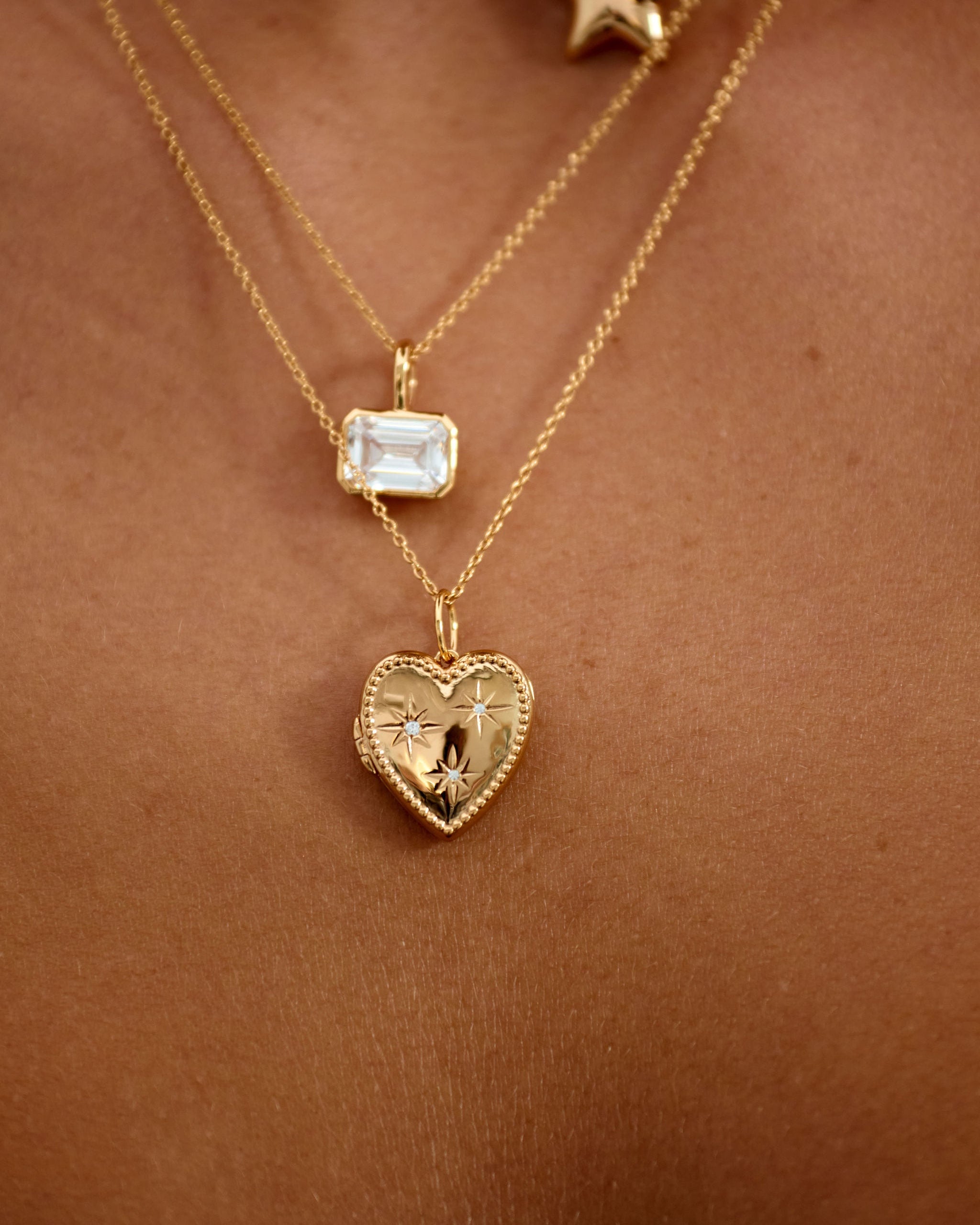 Gold necklaces with heart-shaped and star pendants on a skin background
