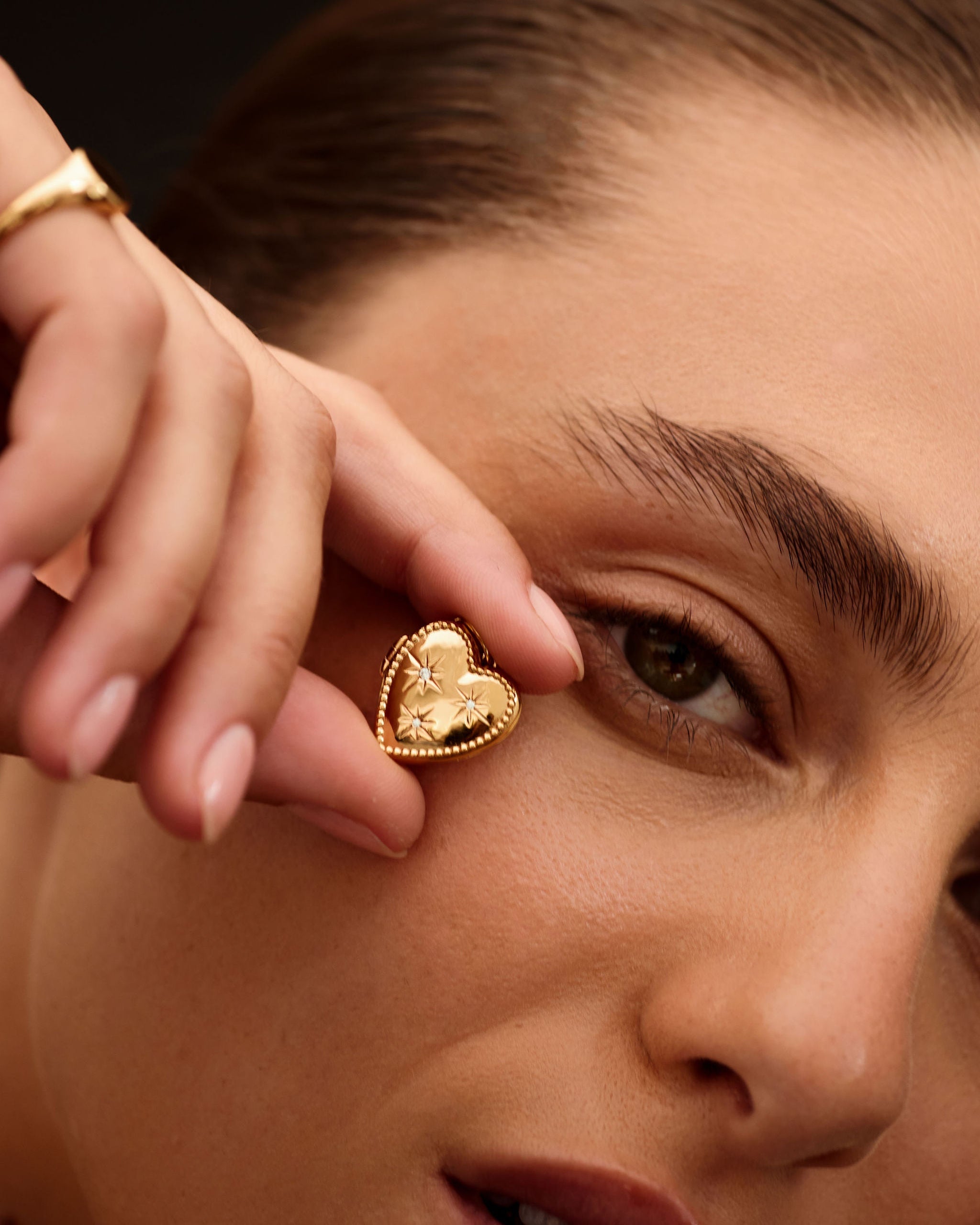 Close-up of a person wearing a gold heart-shaped earring.