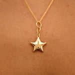Gold star necklace on a person's neck against a brown background