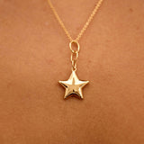 Gold star necklace on a person's neck against a brown background